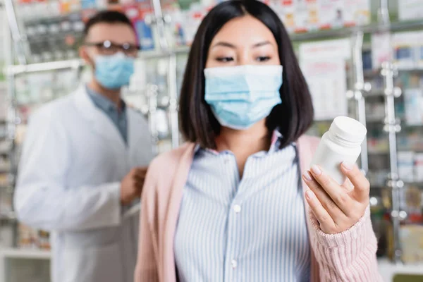 Bottiglia Con Pillole Mano Donna Asiatica Maschera Medica Vicino Farmacista — Foto Stock