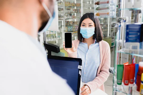 Tıbbi Maskeli Asyalı Kadın Plandaki Bulanık Eczacıya Boş Ekranlı Akıllı — Stok fotoğraf