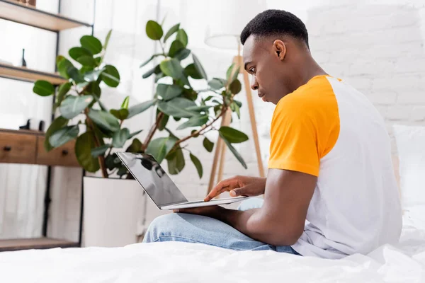 Hombre Afroamericano Joven Usando Ordenador Portátil Con Pantalla Blanco Dormitorio —  Fotos de Stock