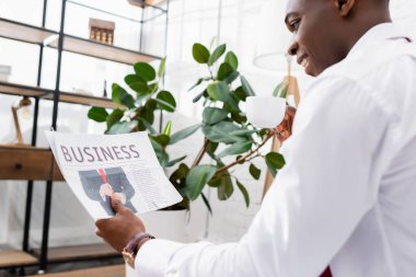 Elinde iş mektupları olan gazete. Elinde fincanı bulanık, gülümseyen Afro-Amerikan iş adamı. 