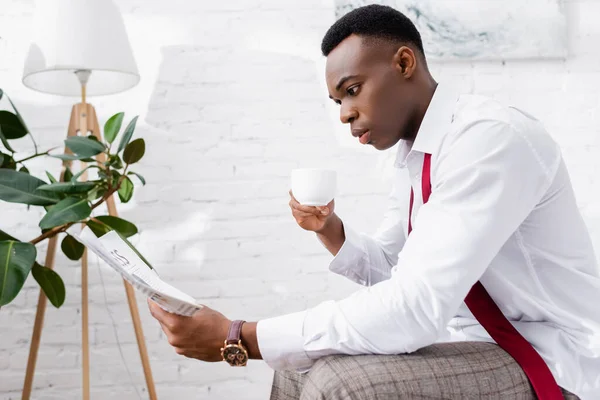 Afrikansk Amerikansk Affärsman Läser Tidningen Och Håller Kopp Kaffe Hemma — Stockfoto