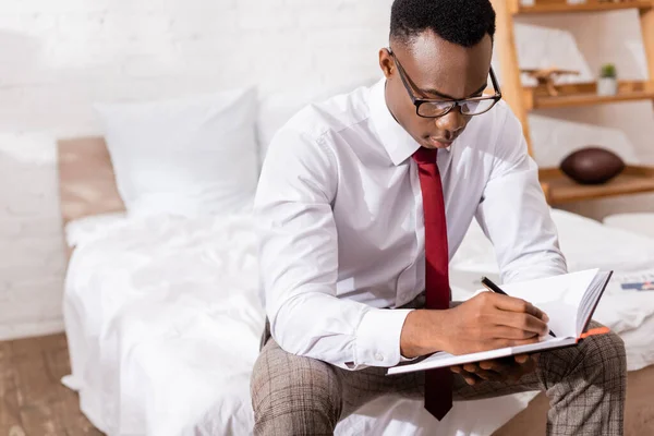 Empresário Afro Americano Óculos Escrevendo Caderno Cama Fundo Embaçado — Fotografia de Stock