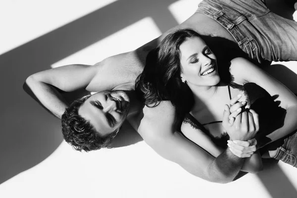 Monocromático Tiro Casal Sexy Sorrindo Enquanto Deitado Fundo Cinza Com — Fotografia de Stock