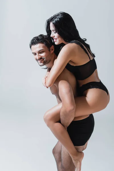 Sonriente Hombre Calzoncillos Piggybacking Sexy Mujer Aislado Gris —  Fotos de Stock