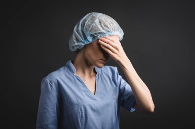 Tıbbi şapkalı yorgun hemşire koyu gri renkli gözlerle izole edilmiş.