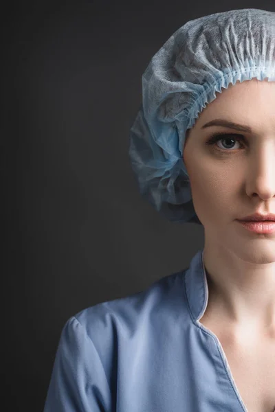 Tıbbi Şapkalı Hemşirenin Koyu Gri Renkli Kameraya Bakarken Kısmi Görüntüsü — Stok fotoğraf