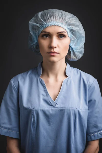 Pielęgniarka Niebieskiej Czapce Medycznej Patrząc Aparat Odizolowany Ciemnoszarym — Zdjęcie stockowe