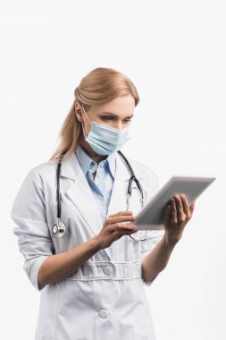 Tıbbi maskeli hemşire ve beyaz önlüklü hemşire beyaz tablet kullanıyor. 