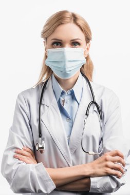 Doktor maskeli ve beyaz önlüklü kolları çapraz duran beyaz tenli. 