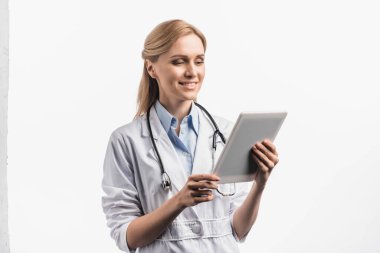 Beyaz önlüklü gülümseyen hemşire beyaza izole edilmiş dijital tablet kullanıyor