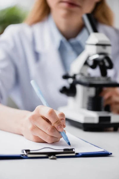 Vista Recortada Escritura Científica Portapapeles Cerca Del Microscopio Sobre Fondo — Foto de Stock