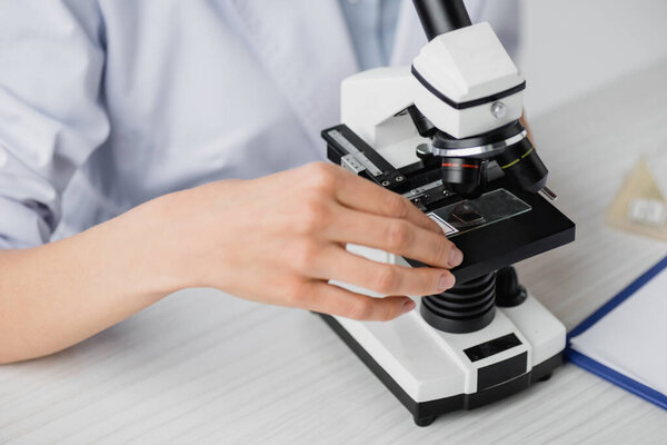 partial view of scientist using microscope in lab