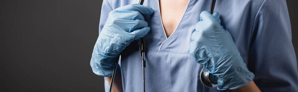 cropped view of nurse in latex gloves adjusting stethoscope isolated on dark grey 