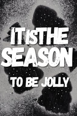 Top view of pine silhouettes covered with sugar powder with it is the season to be jolly lettering  clipart