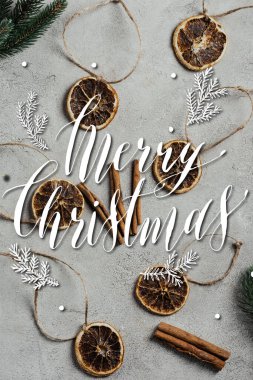 Kurumuş portakal parçalarının üst görüntüsü, telleri, tarçın çubukları ve mutlu noel mektuplarının yanındaki çam dalları. 