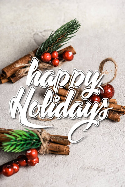 Корица палочки с красными бусами рядом с счастливыми праздниками буквы на сером фоне текстуры