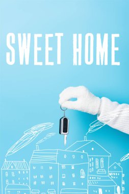 cropped view of woman in white glove holding key near sweet home lettering and houses illustration on blue clipart