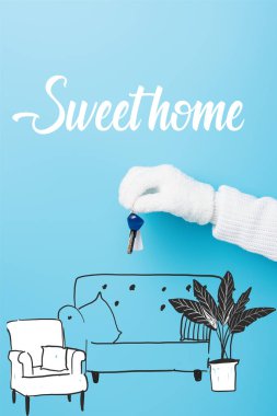 cropped view of woman in white glove holding key near sweet home lettering and sofa illustration on blue clipart
