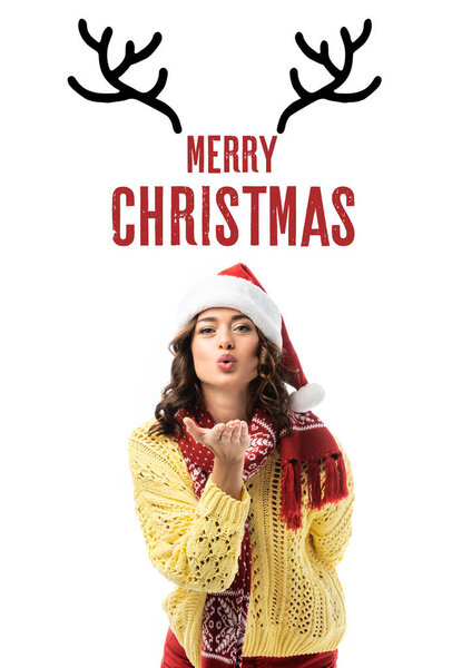 young woman in santa hat and scarf sending air kiss near merry christmas lettering and deer horns illustration on white 
