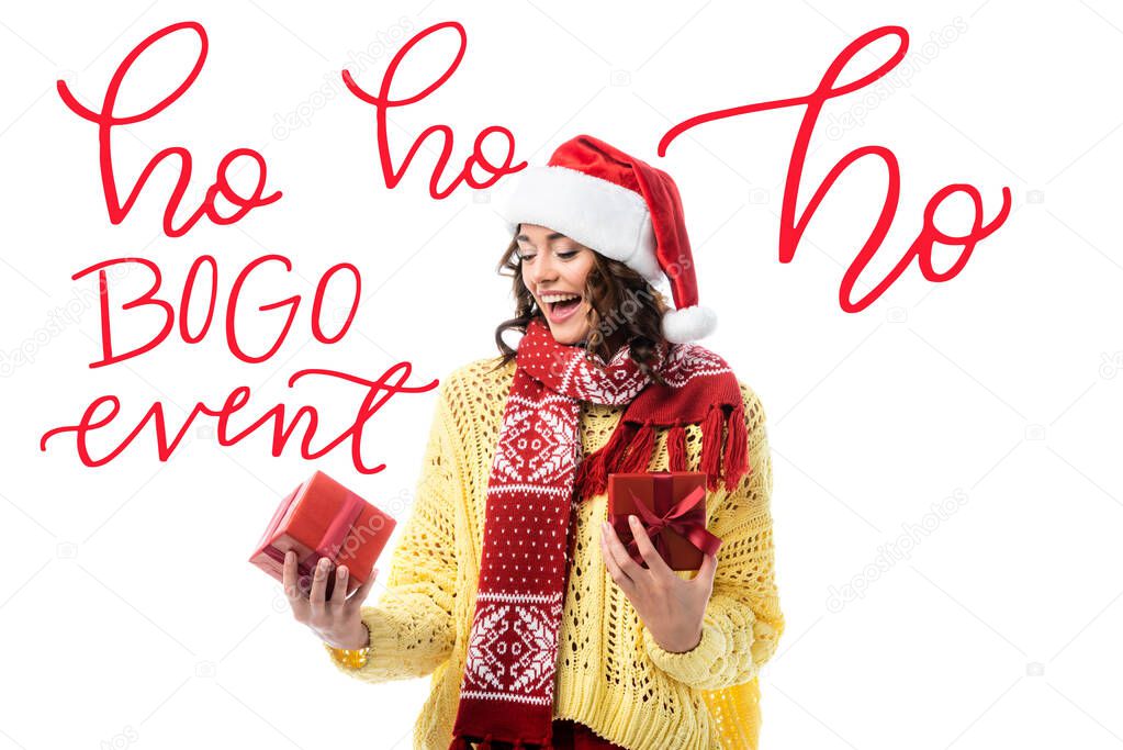 excited woman in santa hat and red scarf looking at present near ho ho ho, bogo event lettering on white