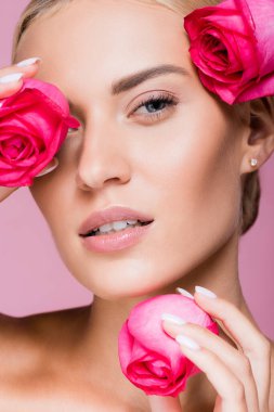 Pembe üzerinde gül çiçekleri olan güzel sarışın kadın.