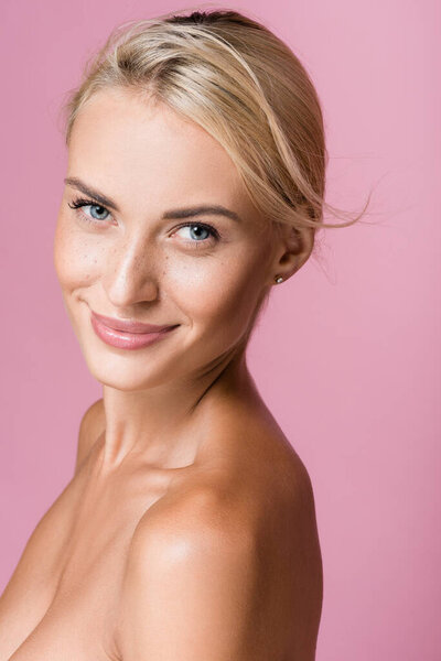 smiling beautiful blonde woman with freckles and bare shoulders isolated on pink
