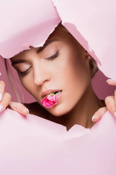 ピンクの紙の穴で口の中にバラを持つ美しい女性 — ストック写真
