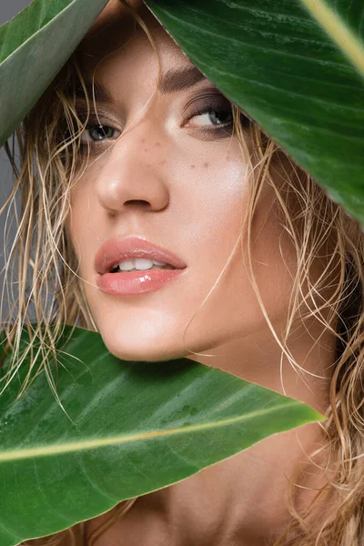 blonde woman with wet hair and green leaf