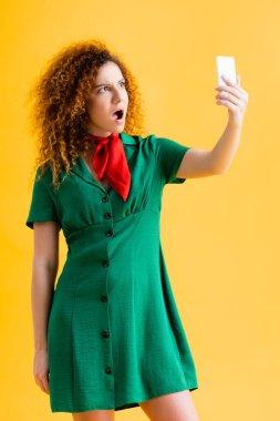 Sarılı selfie çeken yeşil elbiseli genç bir kadın. 