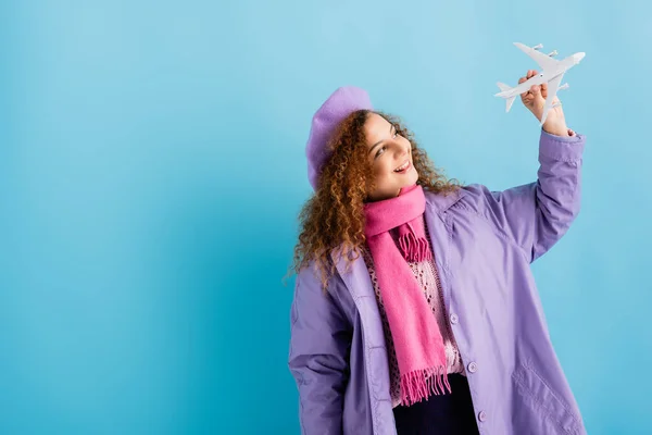 Fröhliche Frau Baskenmütze Schal Und Mantel Mit Blick Auf Spielzeugflugzeug — Stockfoto