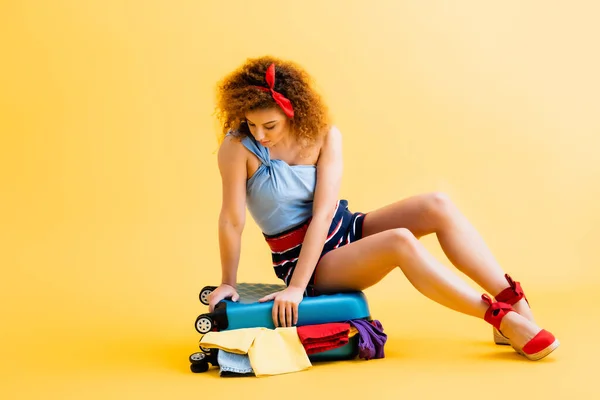 Krullende Jonge Vrouw Zitten Bagage Met Kleding Geel — Stockfoto