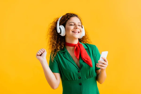 Весела Жінка Бездротових Навушниках Тримає Смартфон Слухаючи Музику Ізольовано Жовтому — стокове фото