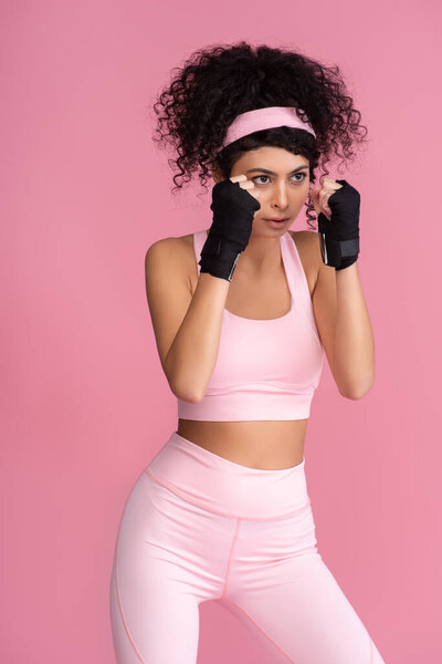 strong young woman in sportswear with bondage on hands isolated on pink