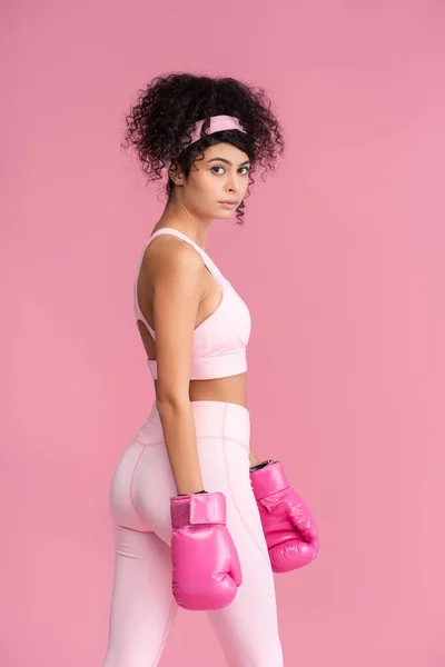 身穿运动服和拳击手套的年轻女子 站在粉色上 凝视着相机 — 图库照片