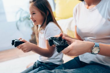 KYIV, UKRAINE - 19 Ekim 2020: Annesi joystick ile mutlu kızının yanında bulanık arkaplan