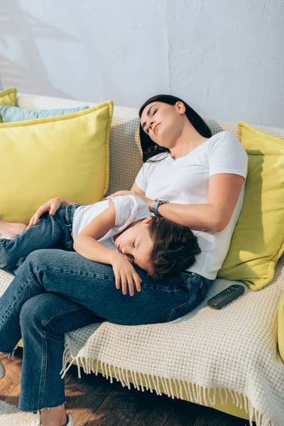 Tired mother and daughter sleeping on couch with remote controller