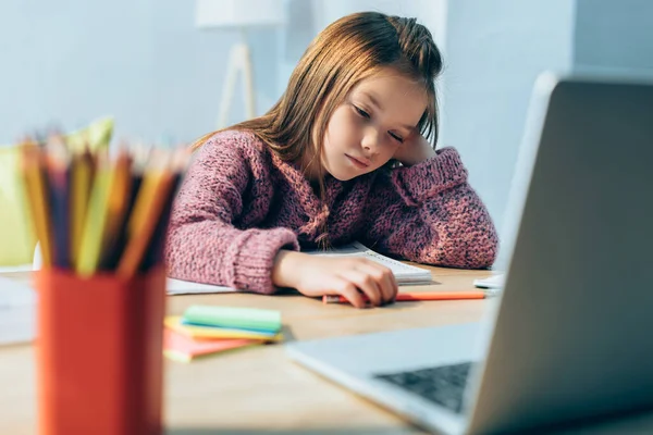 Schläfriges Mädchen Schreibtisch Mit Schreibwaren Und Verschwommenem Laptop Vordergrund — Stockfoto