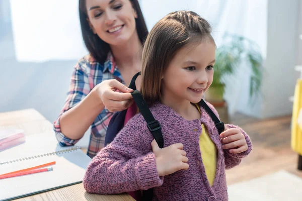 Glimlachende Moeder Zetten Rugzak Dochter Thuis Wazig Achtergrond — Stockfoto