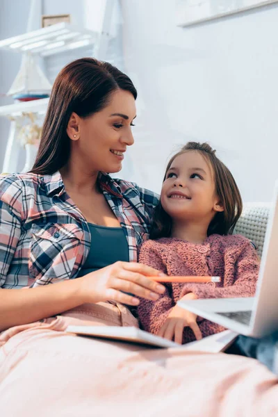 Smiling Mother Looking Daughter While Pointing Pencil Blurred Laptop Foreground — Stock Photo, Image