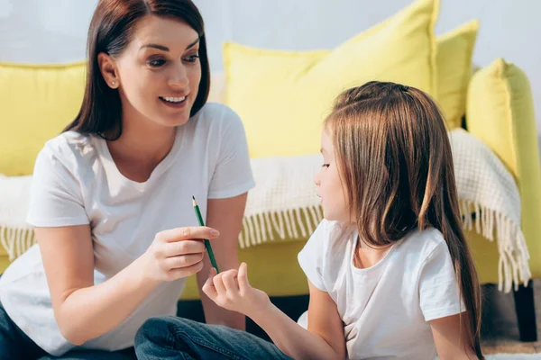 Lächelnde Mutter Mit Buntstift Schaut Tochter Mit Verschwommenem Sofa Auf — Stockfoto