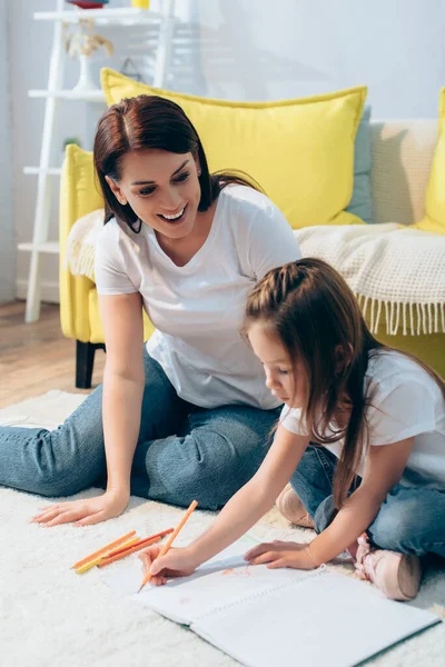 Happy Mother Looking Daughter Drawing Copy Book Floor Blurred Background — Stock Photo, Image
