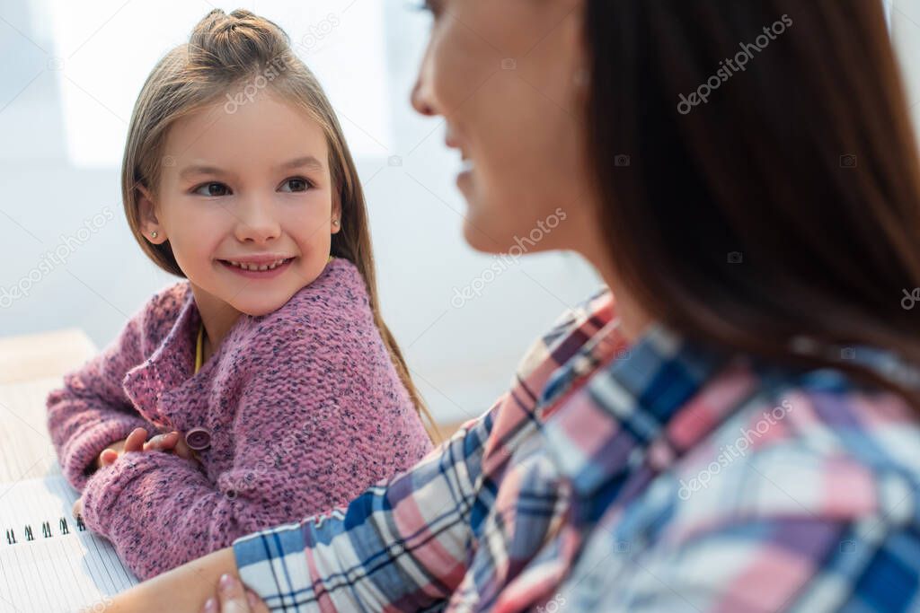 Smiling daughter looking at blurred mother on foreground