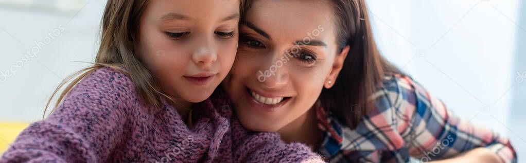 Cheerful mother and daughter looking down on blurred background, banner