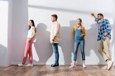 Koridordaki duvarın yanında bekleyen çok kültürlü insanlar. 