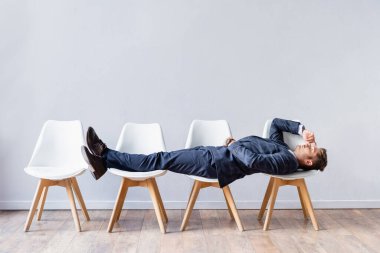 Businessman in suit lying on chairs while waiting job interview  clipart