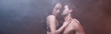 Siyah dantelli sutyen giyen şehvetli bir kadın. Siyah arka planda seksi bir adama sarılıyor.