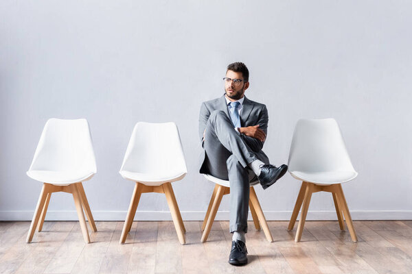 Young businessman sitting with crossed legs on chair in office 