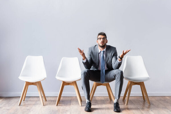 Businessman in suit pointing with hands while waiting job interview in office 