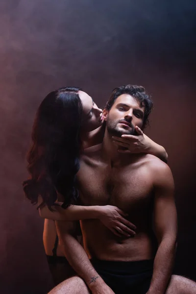 Seductive Woman Embracing Shirtless Muscular Man Looking Camera Dark Background — Stock Photo, Image