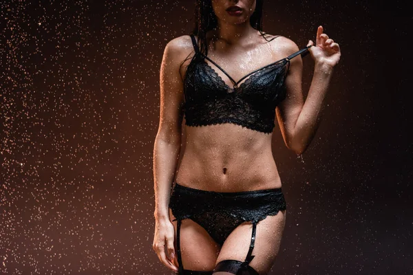 深色背景雨滴下穿着黑色蕾丝内裤和吊带衫的性感女人的局部视图 — 图库照片